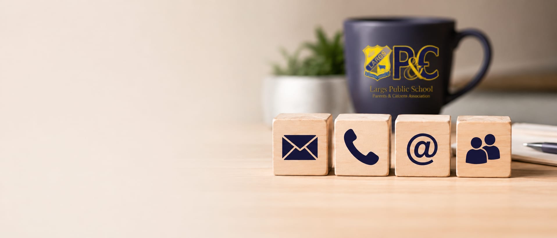 Communication symbols arranged on wooden blocks beside a notebook and a Largs Public School P&C mug.